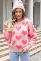 Pink heart pattern knit sweater worn with beanie and casual denim outfit
