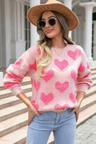 Pink heart pattern knit sweater worn with beanie and casual denim outfit
