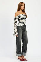 Angled side view of off-shoulder floral mesh top and wide cuff jeans
