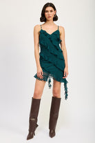 Model wearing emerald green ruffle mini dress with layered ruffles and knee-high boots