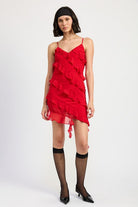 Model styling red ruffle mini dress with sheer black socks and pointed heels