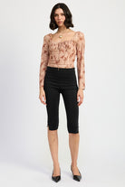 Full front view of model wearing long sleeve floral top styled with black capri pants and kitten heels
