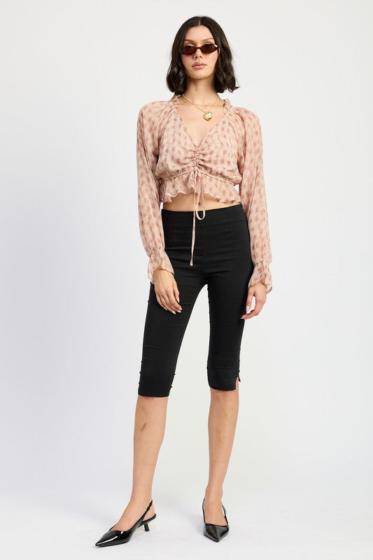 Model in blush plaid ruched crop top, black capri pants, and black kitten heels.