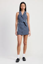 Full front view of model in sleeveless belted mini dress with loafers and socks