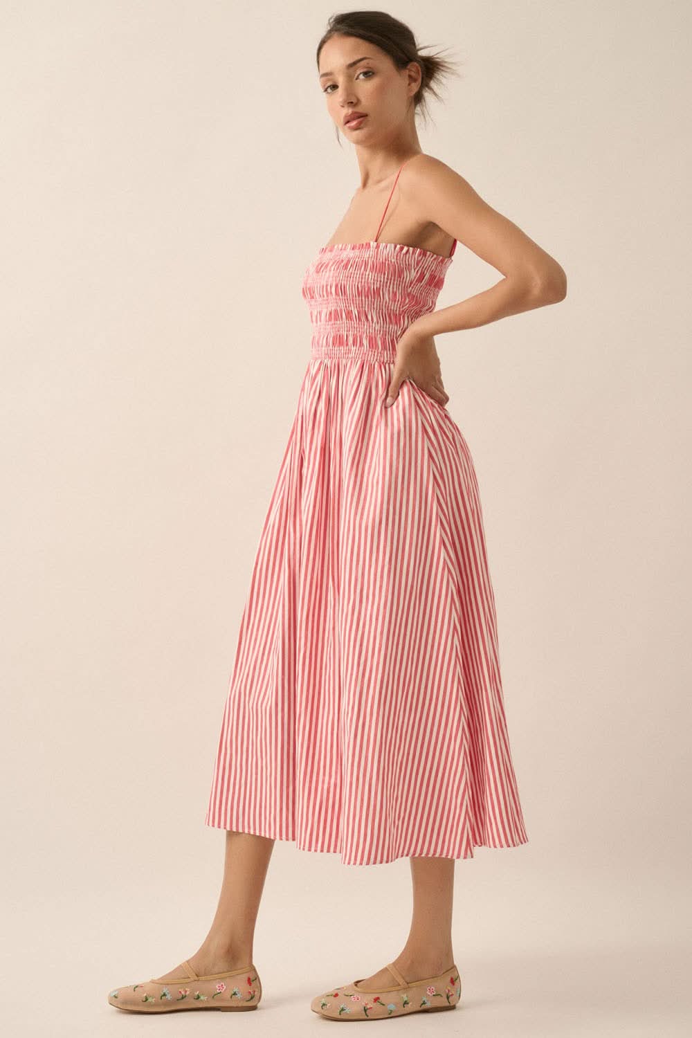 Side profile of model in red and white striped midi dress with gathered skirt and pockets