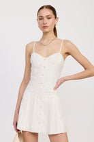 AVAH-Front view of model in ivory pleated mini dress with button-down front and sweetheart neckline