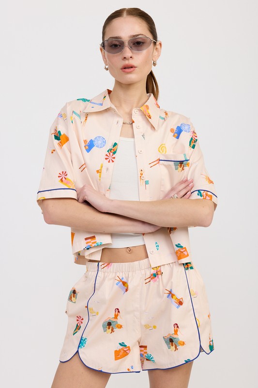 AVAH-Model crossing arms in playful multicolor print cropped shirt, styled with matching shorts and sunglasses.