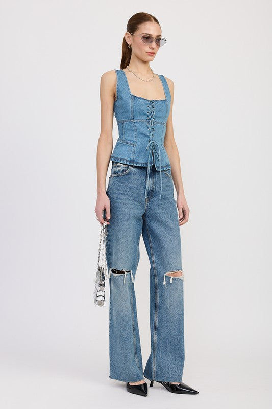 Side angle of denim lace-up top paired with matching jeans and pointed heels