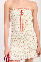 Detail of shirred bodice with red trim and tie-front neckline on cherry print mini dress
