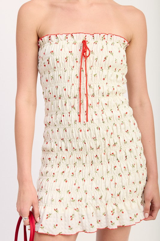Detail of shirred bodice with red trim and tie-front neckline on cherry print mini dress