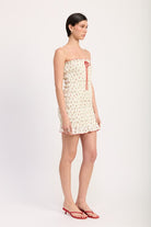 Model in profile wearing floral strapless mini dress with subtle ruffle hem