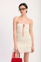 Model wearing strapless cherry print smocked mini dress with red heels and red handbag-AVAH