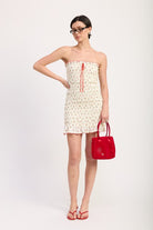 Head-to-toe shot of model in cherry print tube mini dress with red accessories