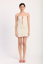 Woman wearing a strapless cherry printed dress on a white background