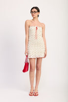 Head-to-toe shot of model in cherry print tube mini dress with red accessories