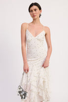 Model holding a silver purse wearing ivory polka dot ruffle dress