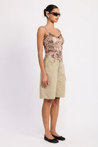 Side view – relaxed fit and long hemline of the sage green shorts