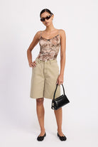 Full outfit front view – sage shorts styled with a printed mesh top and black flats