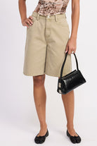 Front view – model wearing sage green cotton Bermuda shorts with hands on hips