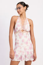Model wearing a pink floral halter mini dress with lace trim -front view

