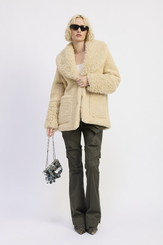 Model wearing a shearling teddy coat with oversized lapels and cozy texture
