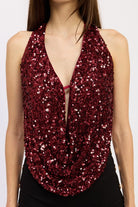 Close-up of red sequin halter top featuring the plunging draped neckline and shimmering sequins.