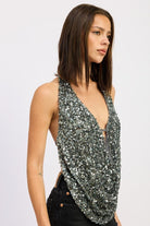 Side angle view of the silver draped sequin halter top showing the low-cut neckline and sequined drape.