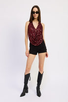 Full-body view of model in red sequin halter top, black shorts, and tall black boots.