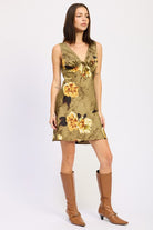 Front view of model wearing olive floral mini dress styled with knee-high boots