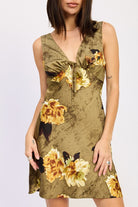 Close-up of olive floral mini dress showing tie-front detail and golden bloom print