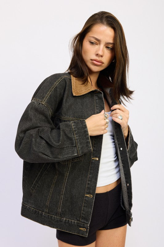 Model wearing oversized black denim jacket from a three-quarter side angle.