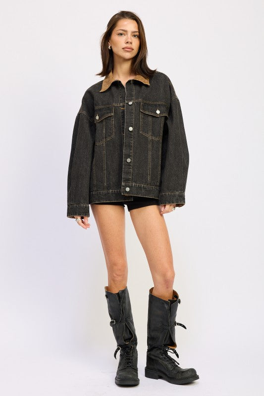 Full body view of model in oversized black denim jacket styled with tall black boots.