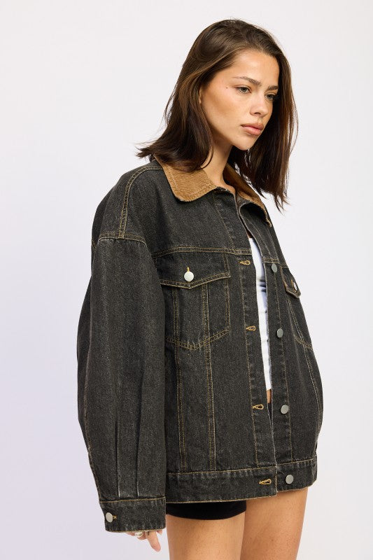 Model wearing oversized black denim jacket from a three-quarter side angle.