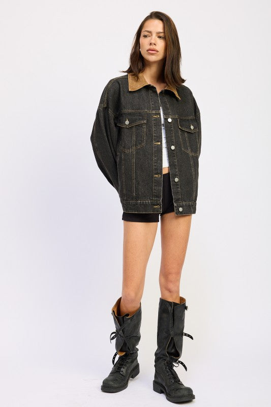 Full body view of model in oversized black denim jacket styled with tall black boots.