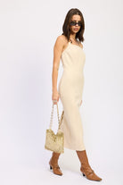 Taupe fitted midi dress with side slit, model holding bag