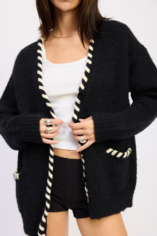 Close-up of cardigan sweater showing button closure and contrast leather trim detail-AVAH