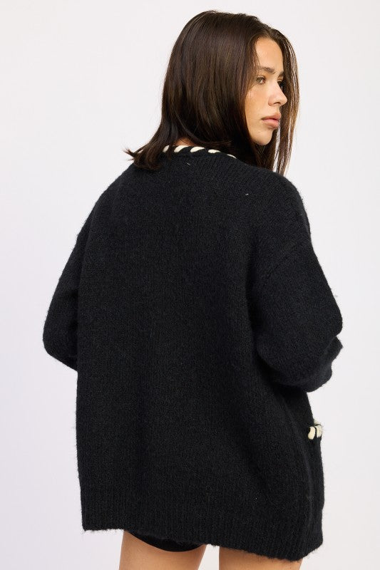 Back view of oversized black cardigan sweater with contrast trim neckline.