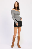 Grey foldover ribbed knit sweater styled with black denim skirt, side view