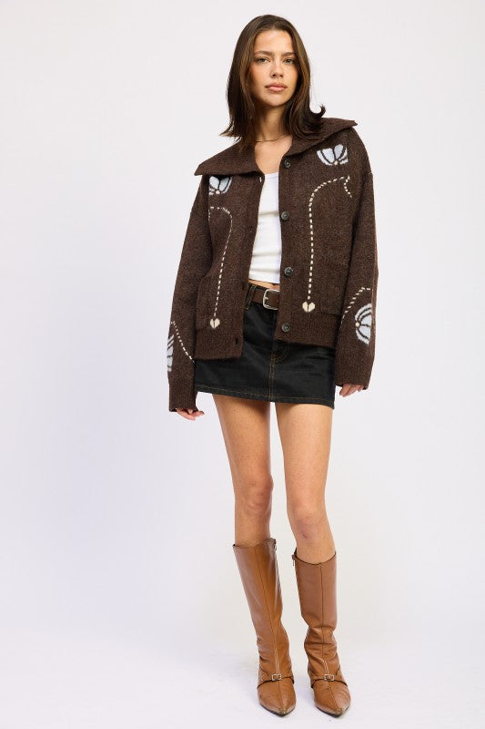 Brown floral knit collared cardigan styled with white tank, black mini skirt, and tall tan boots for a chic fall look-AVAH