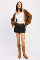 Full outfit with brown cardigan, black denim mini skirt, and tan boots.
