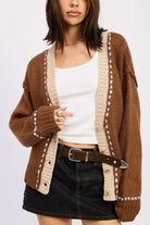Close-up of brown two-tone knit cardigan showing cream border and button detail.
