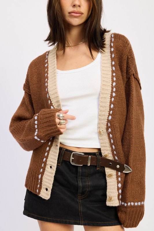 Close-up of brown two-tone knit cardigan showing cream border and button detail.
