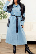 Front view of denim trench coat with black faux leather panels and belted waist
