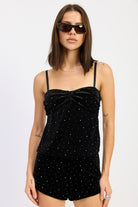 Model wearing a black velvet rhinestone cami top with thin straps and twist-front detail, paired with matching shorts.