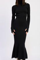 Close-up of black knit turtleneck dress with curve-hugging fit and flared hem.