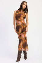 Rust mixed print maxi dress captured in motion, highlighting fluid fit and colorful blurred pattern.
