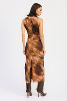 Back view of rust abstract print maxi dress with subtle ruching and slit hemline, paired with tall brown boots.