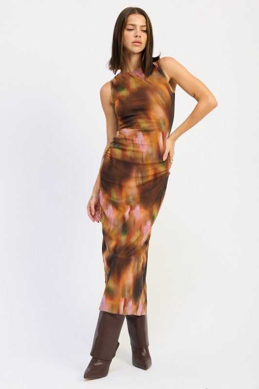 Model in rust abstract sleeveless maxi dress posing with one hand on hip, showing body-skimming silhouette.