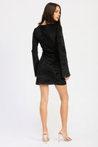Back view of black textured mini dress with fitted cut.