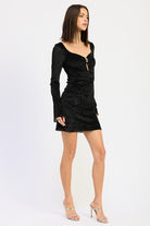 Side view of black long-sleeve mini dress with sculpted neckline.
